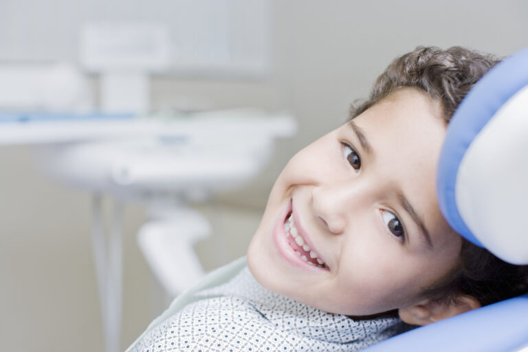 Boy smiling and sitting in dentists chair